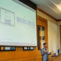 man in a suit presenting to full room